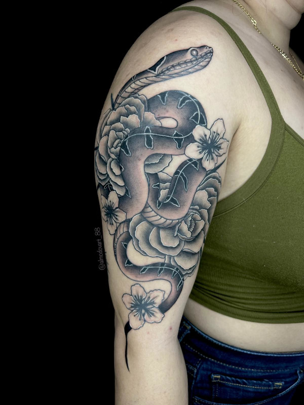 Black and grey fine line upper arm tattoo fo a snake twining through peony and poppy flowers by artist Lita Almodovar at Sacred Mandala Studio in Durham, NC.